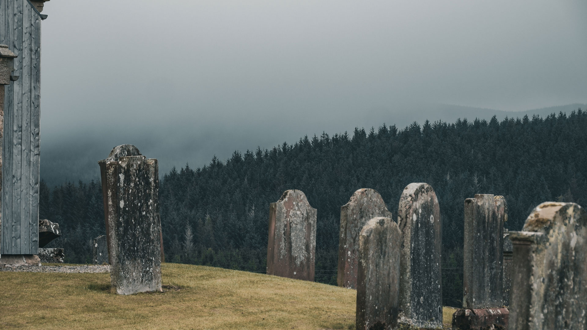 Historic gravestones beside Crawfordjohn church with the surrounding hills beyond
